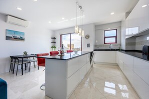 A modern kitchen with white cabinets, a large island, and pendant lighting. - Apartment 'Prime Suite - Albufeira, Algarve' with Sea View, Wi-Fi and Air Conditioning (Albufeira)