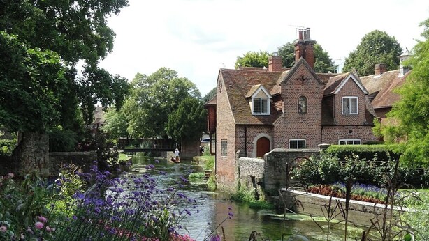 A riverside building with a brick facade, a stone bridge, and a garden with water lilies. - Cosy & Stylish Canterbury Apartment | Free Parking (Canterbury)