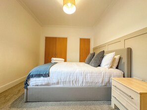 Une chambre à coucher avec un lit, des tables de chevet et une armoire.