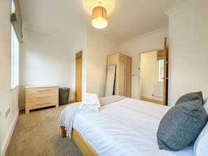 A bedroom with a bed, a dresser, a wardrobe, a mirror, and a window. - Cosy & Stylish Canterbury Apartment | Free Parking (Canterbury)