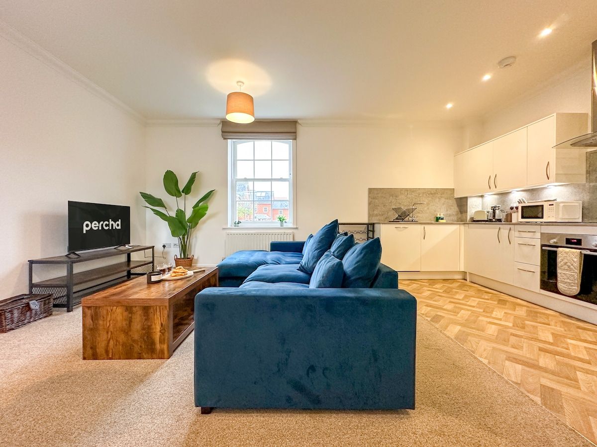 A modern living room with a blue sofa, a wooden coffee table, and a television.