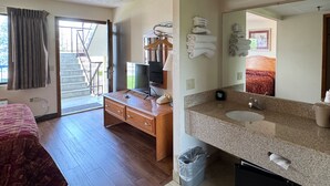 Una habitación de hotel con cama, escritorio, televisión y baño.