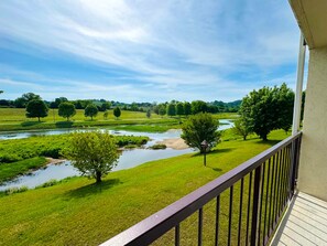 A balcony with a view of a river, grassy fields, and trees. - Landmark Inn On The River (Sevierville)