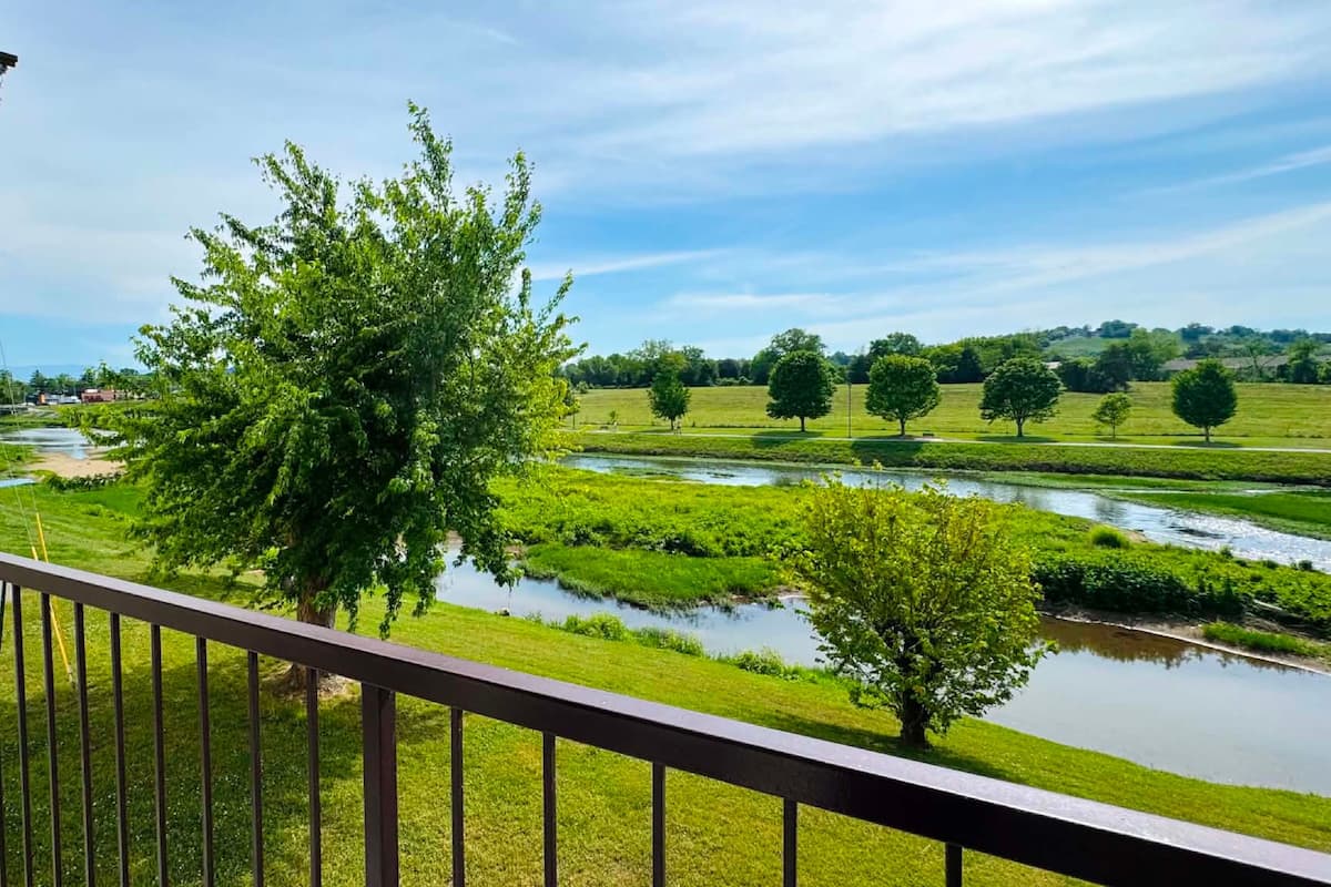 A balcony with a view of a river, trees, and a distant landscape.