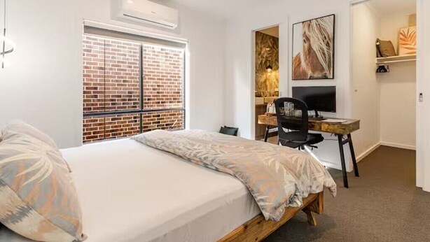 Une chambre avec un lit, un bureau, une chaise, une télévision et un mur en briques.