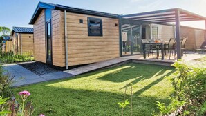 A modern single-story house with a covered patio, a small lawn, and a clear sky. - Koudekerke Escape Near Dunes (Koudekerke)
