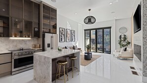 Una cocina moderna con una isla central, electrodomésticos de acero inoxidable y un amplio ventanal.