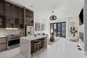 Una cocina moderna con una isla central, electrodomésticos de acero inoxidable y un amplio ventanal.