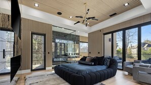 Un dormitorio moderno con una cama grande, televisor y balcón con vistas.