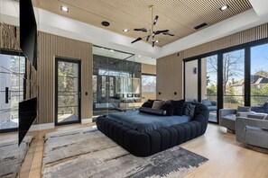 Un dormitorio moderno con una cama grande, televisor y balcón con vistas.