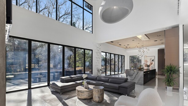 Un amplio salón con ventanas grandes, un conjunto de sofás modernos y un diseño minimalista.