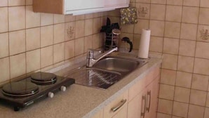 A kitchen with a sink, stove, cabinets, and a tiled backsplash.