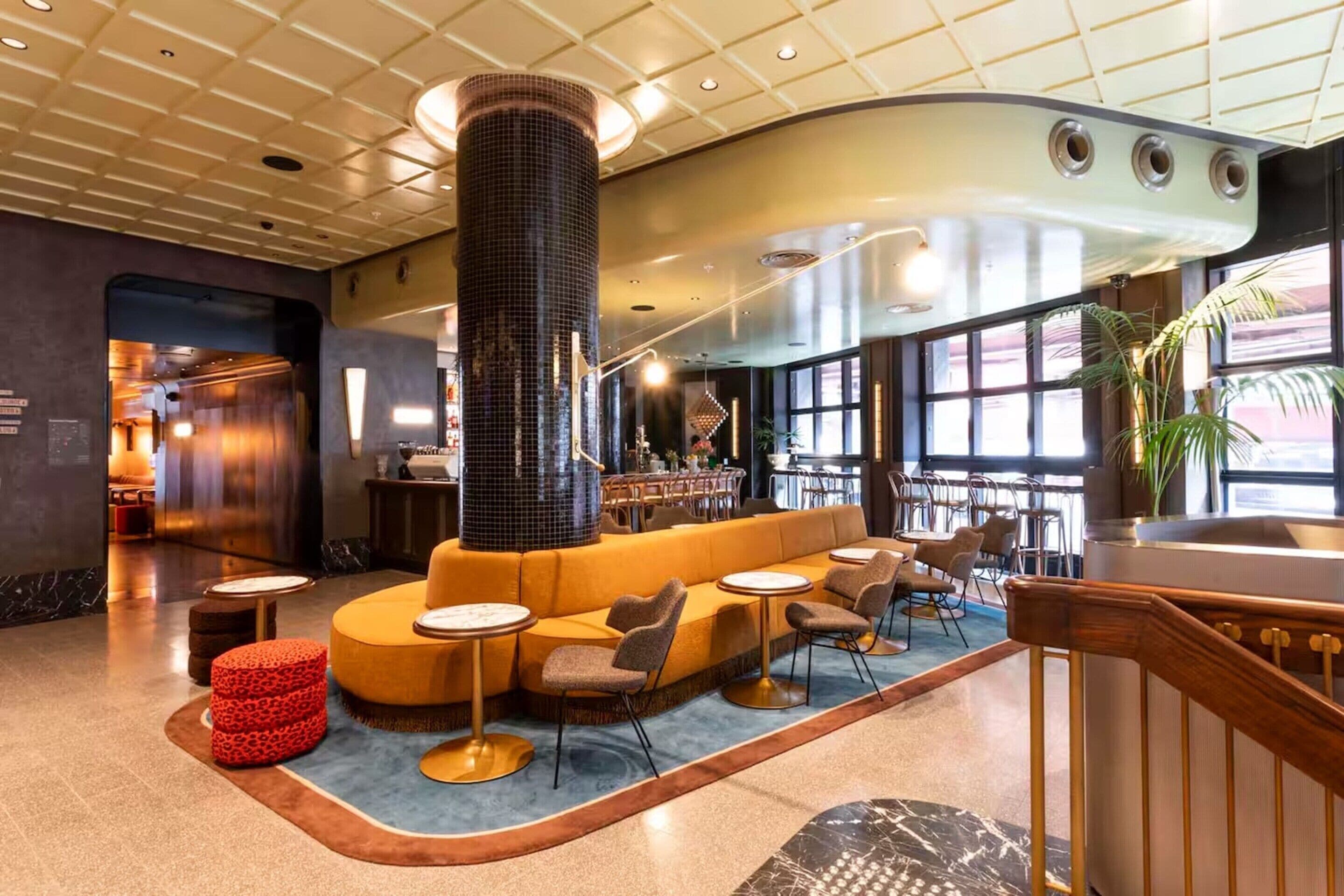 Een ontvangsthal met een centrale pilaar, zitgedeeltes en een bar.