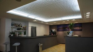 Ein Empfangsbereich mit Bar, Mülleimer und einer Decke mit Lochmuster.