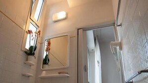 Ein Badezimmer mit weißem Waschbecken, Spiegel und Duschbereich.