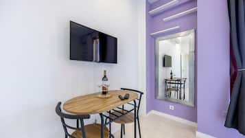 A dining area with a wooden table, chairs, a wine bottle, and a remote control.