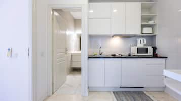A modern kitchen with white cabinets, a microwave, and a kettle on the countertop.