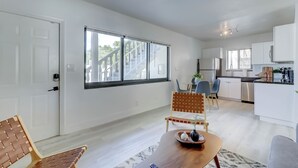 Eine moderne Küche mit weißen Schränken, einem Edelstahl-Kühlschrank und einem Essbereich mit Holztisch und Stühlen.