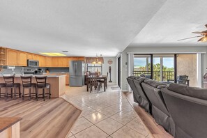 A modern kitchen with a central island, bar stools, and a dining area with a table and chairs. - Sea Club #42 - Stellar Escape (Indian Shores)