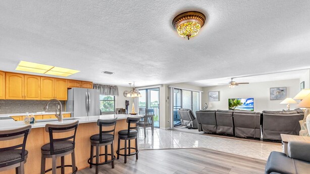 A modern kitchen with a bar area, a dining area with a sofa, and a view of the outdoors. - Sea Club #42 - Stellar Escape (Indian Shores)