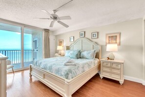 A bedroom with a bed, a nightstand, a dresser, a ceiling fan, and a view to the outside. - Sand Castle II #2603 - Premier (Indian Shores)