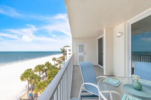 A balcony with a view of the beach, a table with chairs, and a door. - Sand Castle II #2603 - Premier (Indian Shores)
