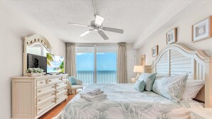 Ein Schlafzimmer mit Bett, Kommode, Fernseher und einem Balkon mit Blick.
