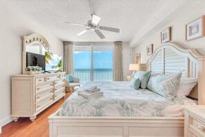 A bedroom with a bed, a dresser, a TV, and a balcony with a view. - Sand Castle II #2603 - Premier (Indian Shores)