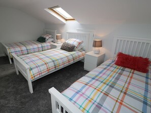 A bedroom with two beds, a skylight, white furniture, and a radiator. - The Cartwheel (Narberth)