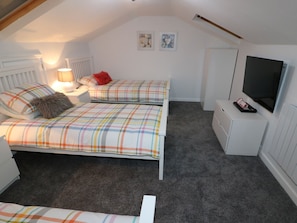 Un dormitorio con dos camas, televisión, lámpara y una obra de arte en la pared.