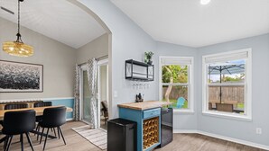 Une cuisine avec un coin repas, un meuble à vin et une vue sur le jardin arrière.