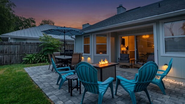 Une terrasse avec mobilier d’extérieur, un foyer et un espace couvert doté de portes-fenêtres coulissantes.