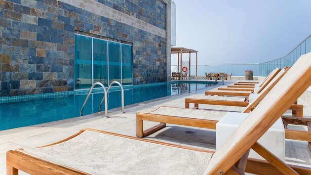 A poolside area with lounge chairs, a glass door, and a view of the sea. - Palmetto Beach - ILLUMINATO (Cartagena)