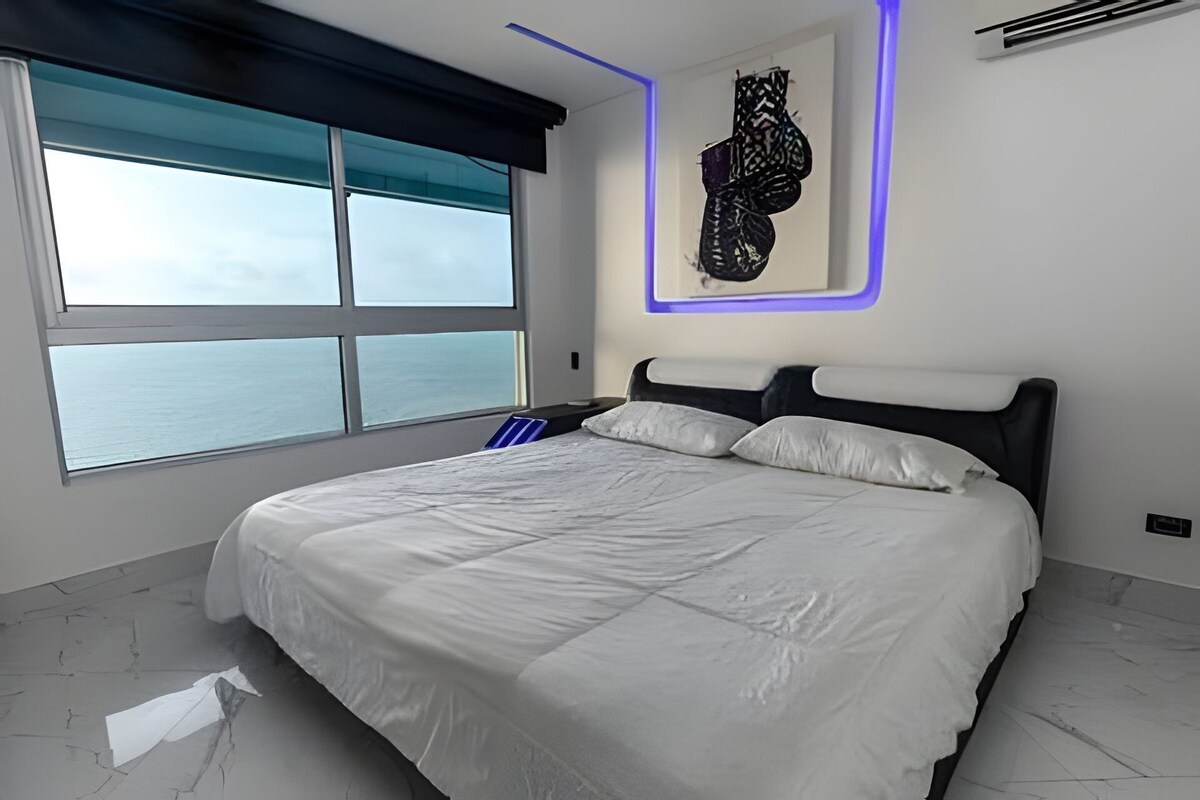 Ein Schlafzimmer mit einem großen Bett, Meerblick und einem modernen Wanddesign.