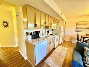 A compact kitchen with wooden cabinets, a microwave, a refrigerator, and a coffee maker. - Lake Taneycomo View -  Cozy 1BR Condo - Fireplace (Branson)