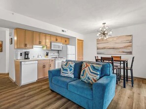 A compact living space with a kitchenette, a dining area, and a sofa with patterned cushions. - Lake Taneycomo View -  Cozy 1BR Condo - Fireplace (Branson)