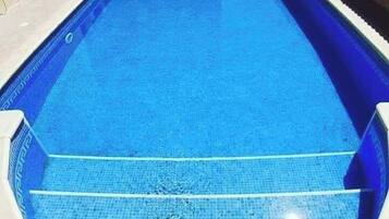 Una piscina rectangular con agua azul cristalina, rodeada por un solárium empinado.