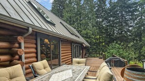 Een blokhut met terras, buitenmeubels en een barbecueplek.