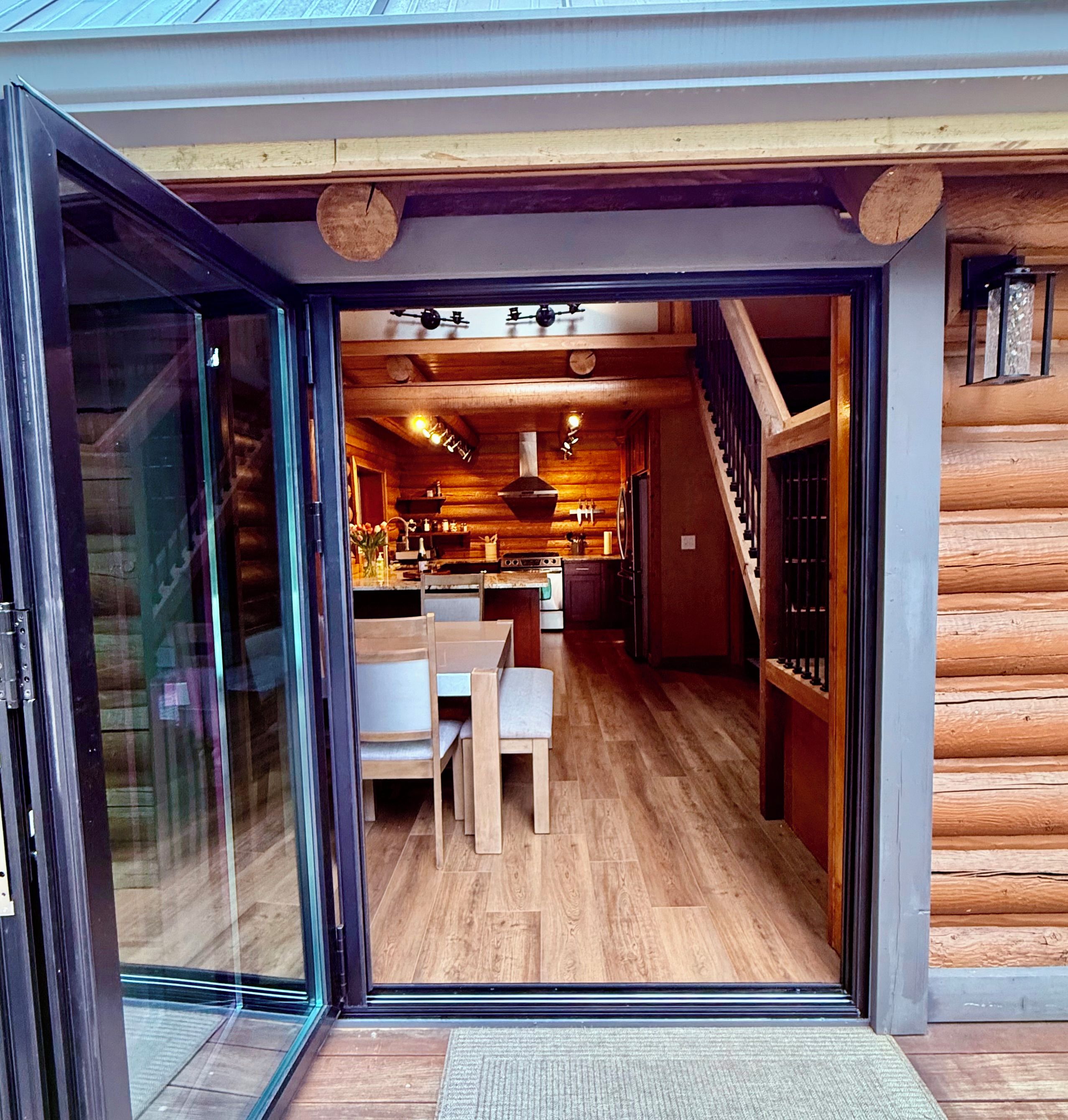 Eine moderne Küche mit Holzschränken, ein Essbereich mit Tisch und Stühlen sowie eine Treppe, die zu einer oberen Ebene führt.