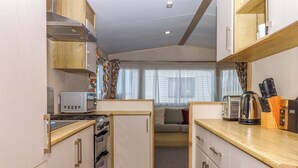 Una cocina compacta con microondas, tostadora, hervidor y bloque de cuchillos.