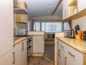 A compact kitchen with a microwave, toaster, kettle, and knife block. - 213 Seaview Caravan (Paignton)