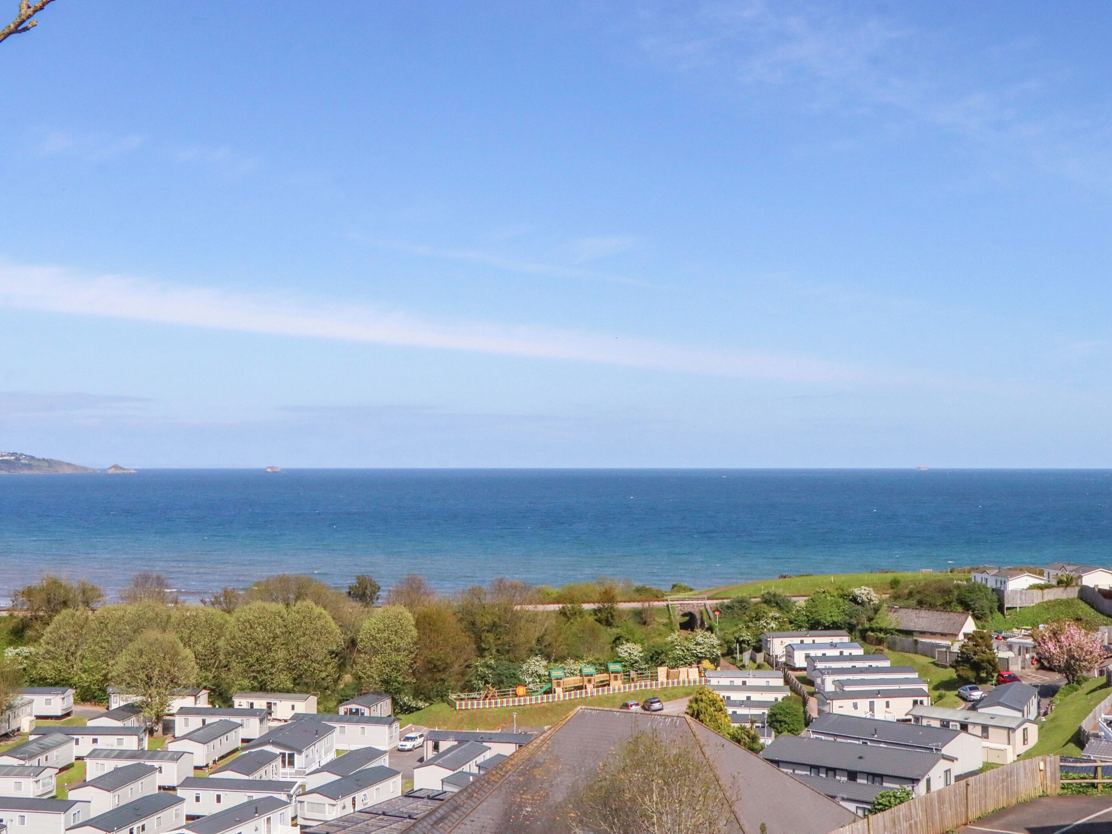 A coastal residential area with mobile homes, a clear sky, and the sea in the background.