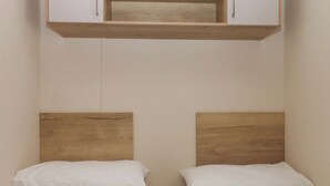 Un dormitorio con dos camas individuales, cabeceros de madera, ropa de cama blanca y una mesita de noche de madera.