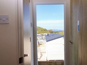 A doorway leading to a balcony with a view of a hillside and distant buildings. - 213 Seaview Caravan (Paignton)