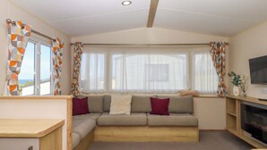 Una sala de estar acogedora con un sofá, televisión y ventana con cortinas.