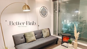 Een moderne woonkamer met een grijze bank, een vloerlamp, een wandklok en een open haard.