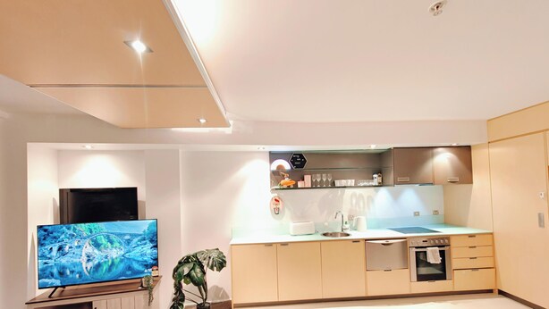 Een moderne keuken met een flatscreen televisie, een inbouwoven en een klein spoelgedeelte.