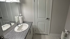 A bathroom with two sinks, a toilet, and a door.