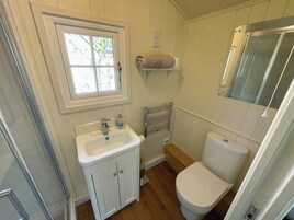 Un baño con lavamanos blanco, inodoro, ventana y toallero.