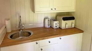 A small kitchenette with a wooden countertop, a stainless steel sink, a toaster, and a kettle. - The Shepherds Hut (Wallingford)